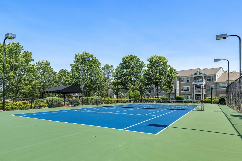 a tennis court with a fence and a building in the background at The Preserve at Ballantyne Commons in Charlotte, NC.