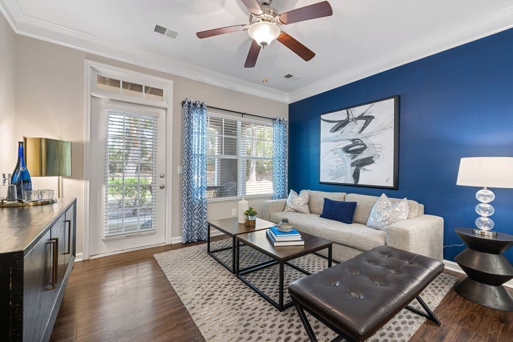 a living room with a couch , coffee table , ottoman and ceiling fan at The Preserve at Ballantyne Commons in Charlotte, NC.