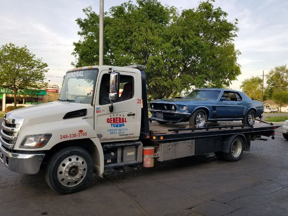 Blue classic car being towed on a flatbed truck with 