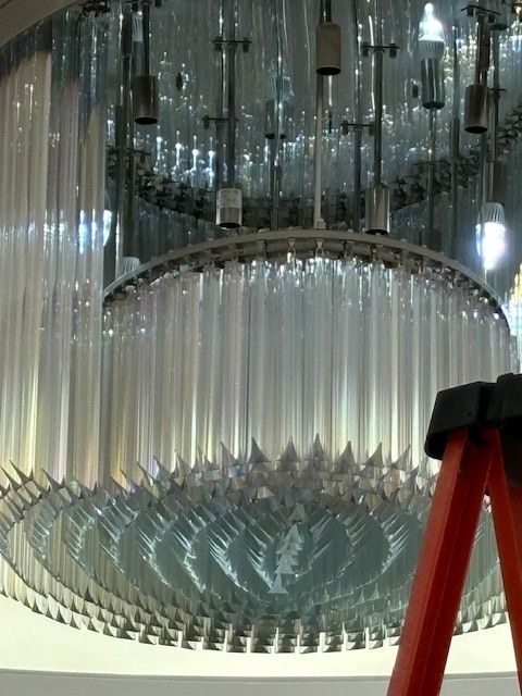 A man is installing a light fixture on the ceiling.