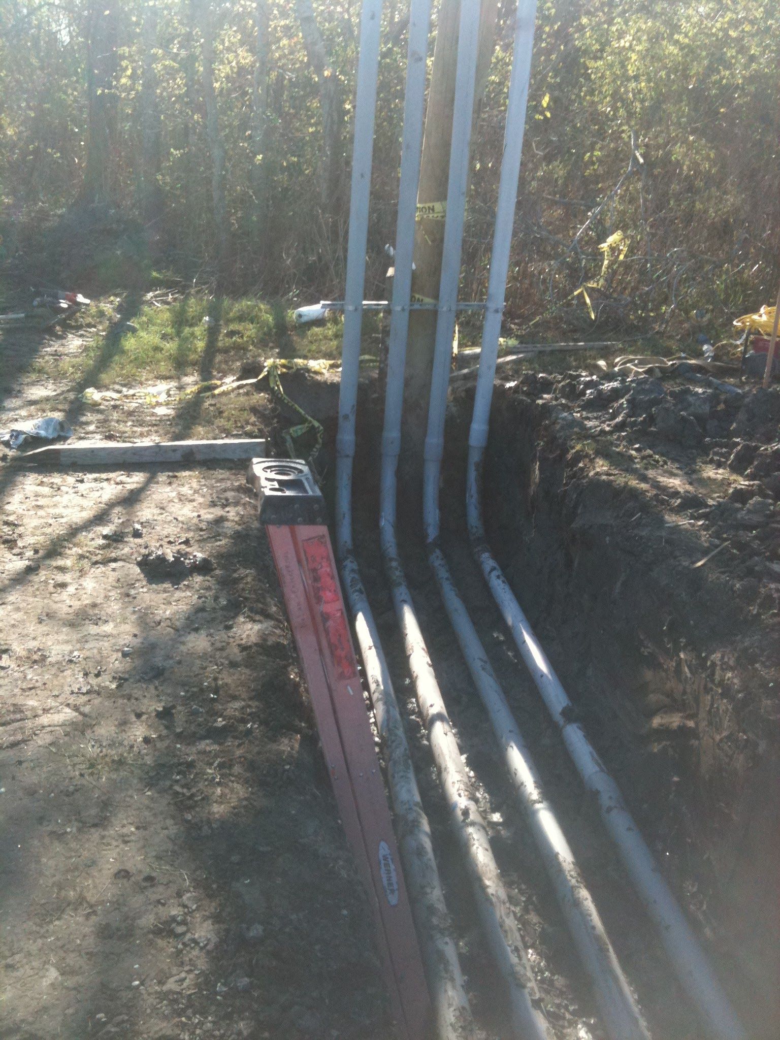 A bunch of pipes are laying in the dirt