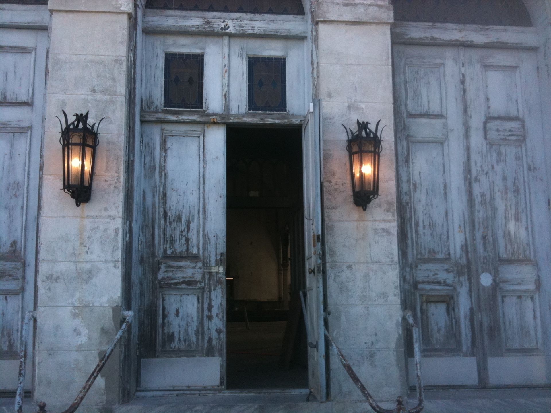 A building with the door open and two lanterns on the side