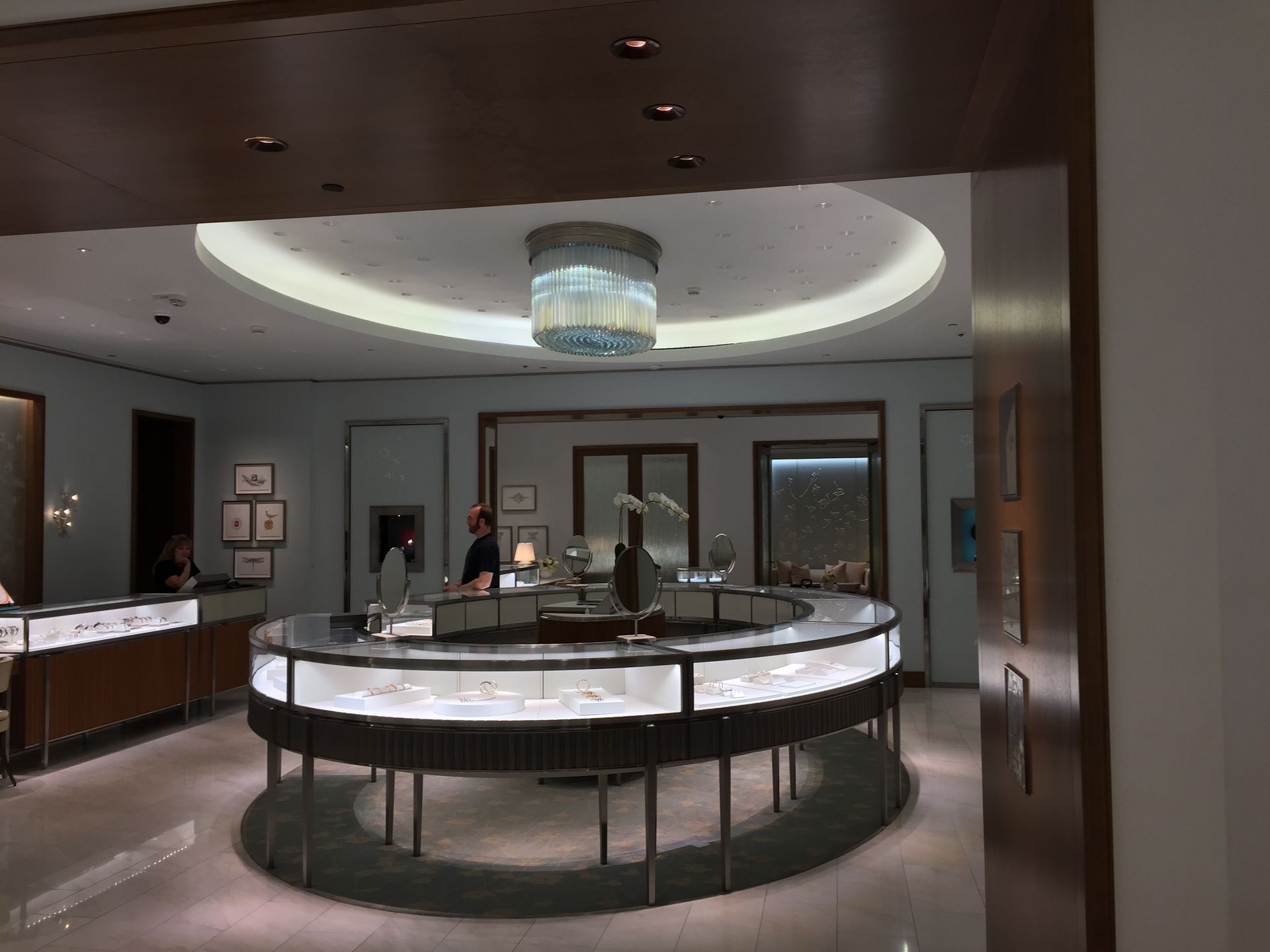 A jewelry store with a round table and a chandelier hanging from the ceiling.
