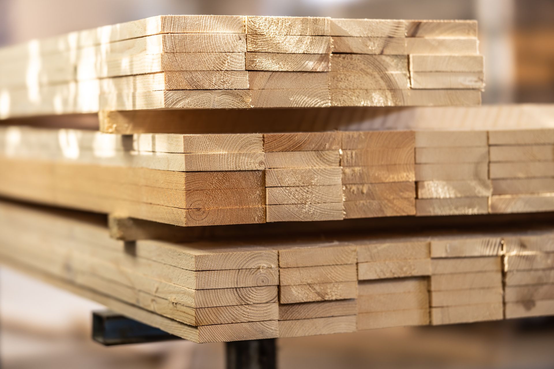 A pile of wooden planks sit on the inside of a workshop.