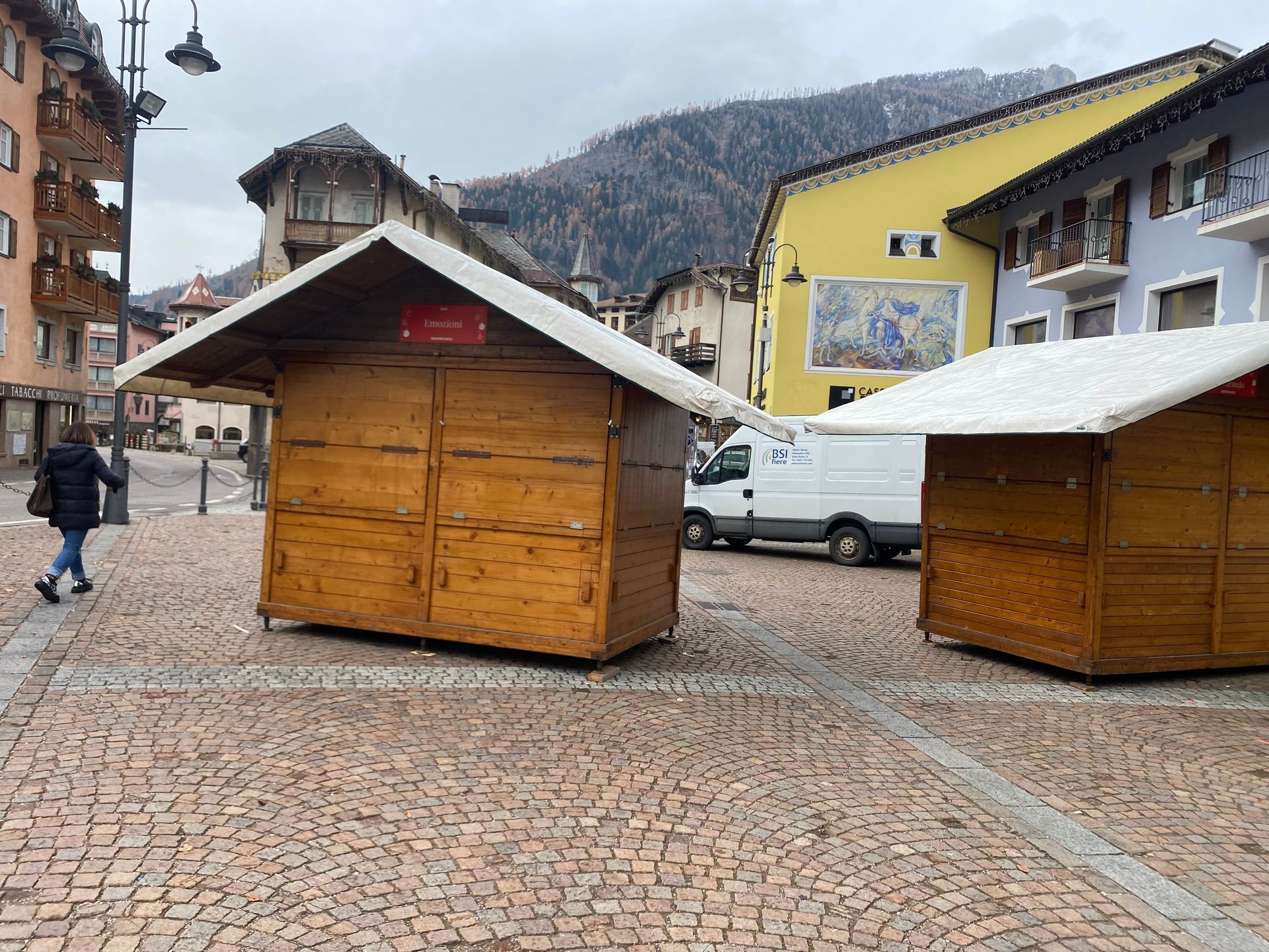 Due capanne di legno sono situate su una strada acciottolata di fronte a un edificio.