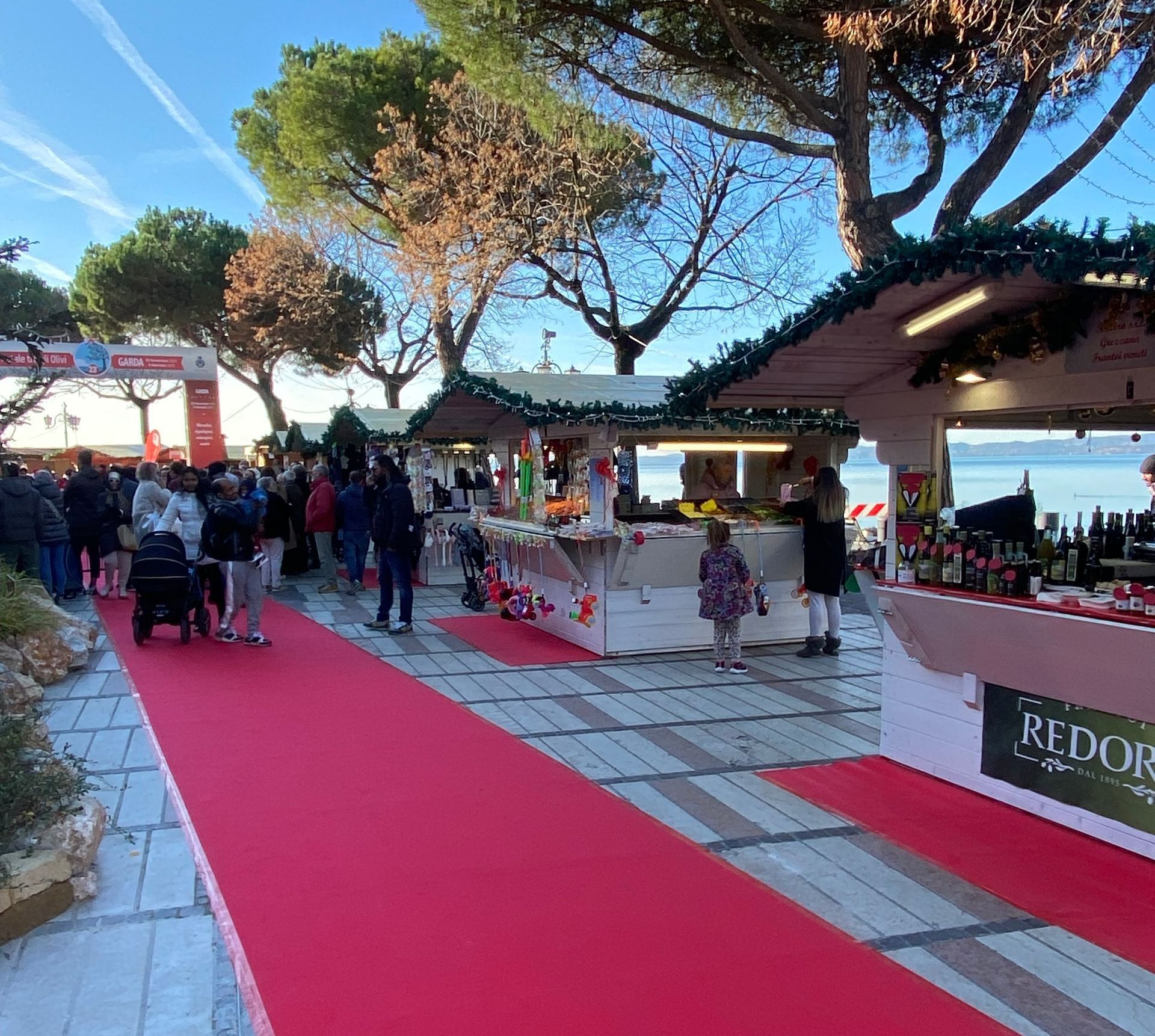 Un gruppo di persone è in piedi attorno a un tappeto rosso in un mercatino di Natale.