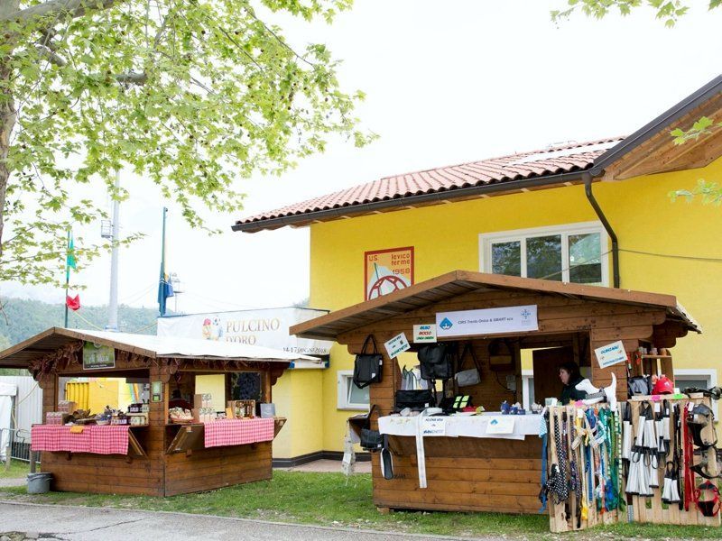 Un edificio giallo con due chioschi di legno di fronte