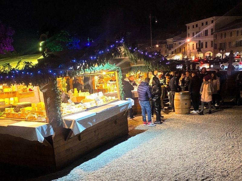 Un gruppo di persone è in piedi attorno a un mercatino di Natale di notte.