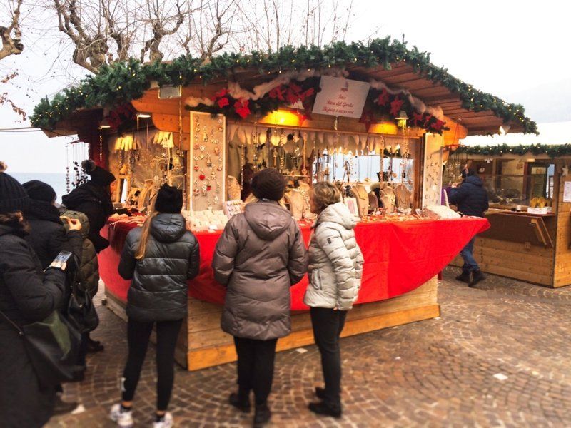 Un gruppo di persone è in piedi davanti a un mercatino di Natale.