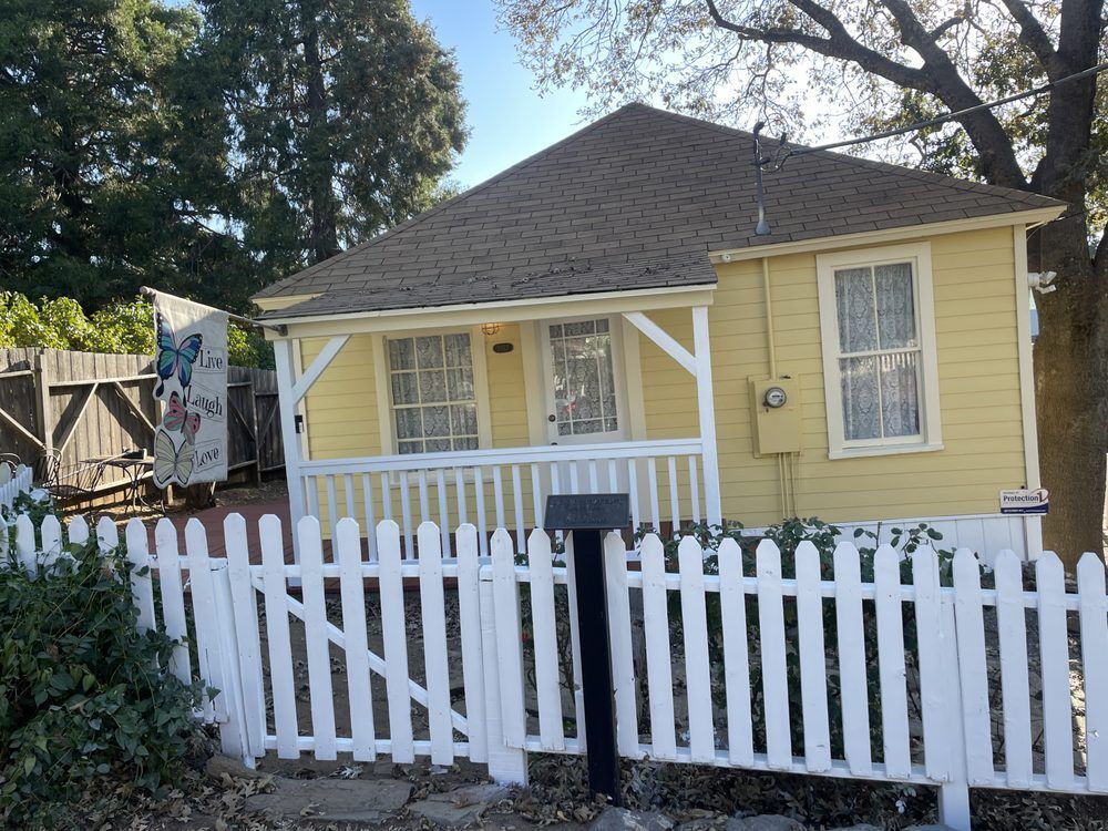 Yellow house with white picket fence and porch.