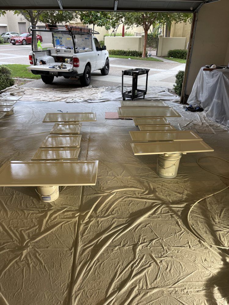 White truck, cabinets, and painting supplies in a garage, covered with beige drop cloths.
