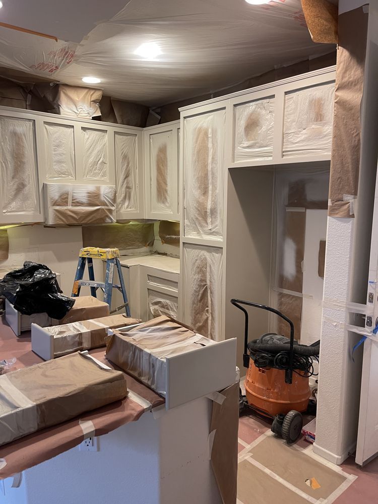 Kitchen cabinets being painted; plastic covering protecting the surfaces.