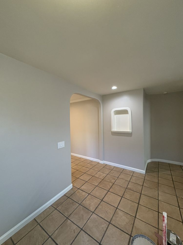 Empty room with tile floor, gray walls, arched doorway, and built-in shelf.