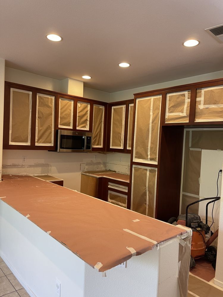 Kitchen with brown cabinets covered in paper, undergoing renovation.