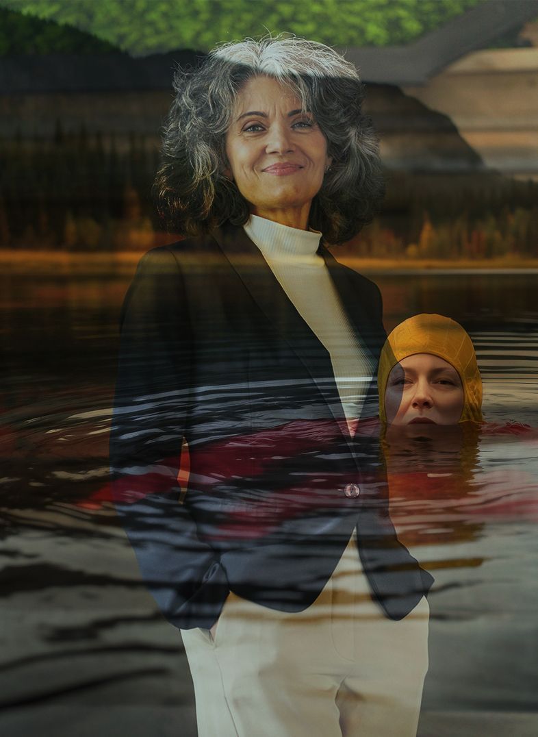 Woman in blazer, smiles; swimmer in yellow cap and water visible. Lakeside setting.