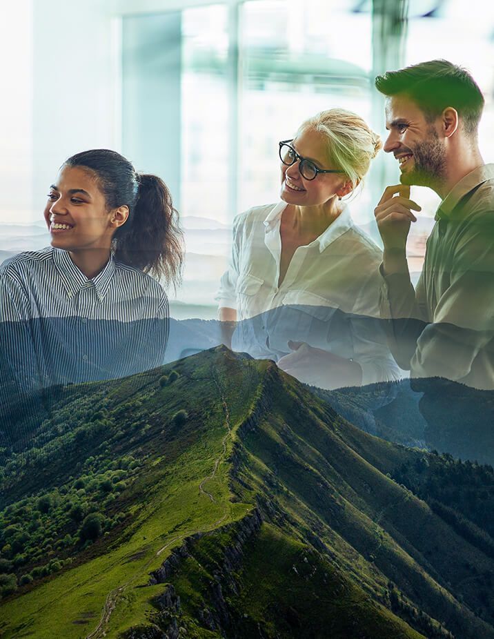 Three professionals smiling in an office, overlaid with a mountain ridge.