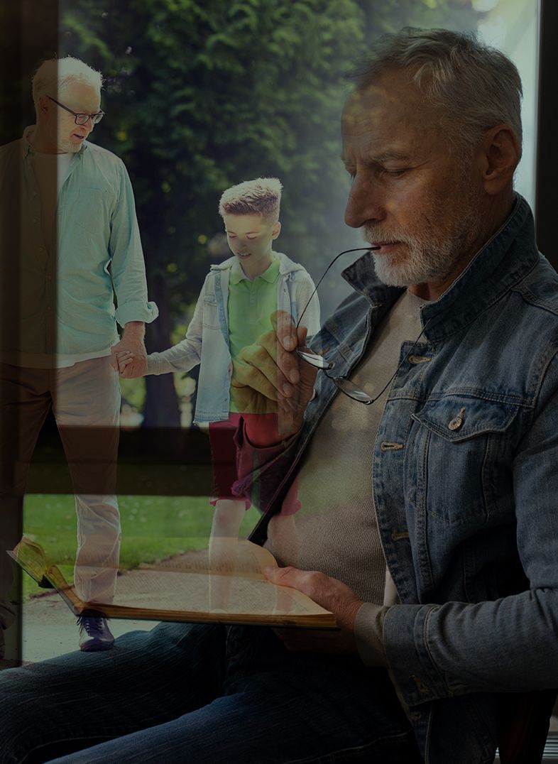 Man drawing, holding glasses, with a memory of himself as a young man with a child.