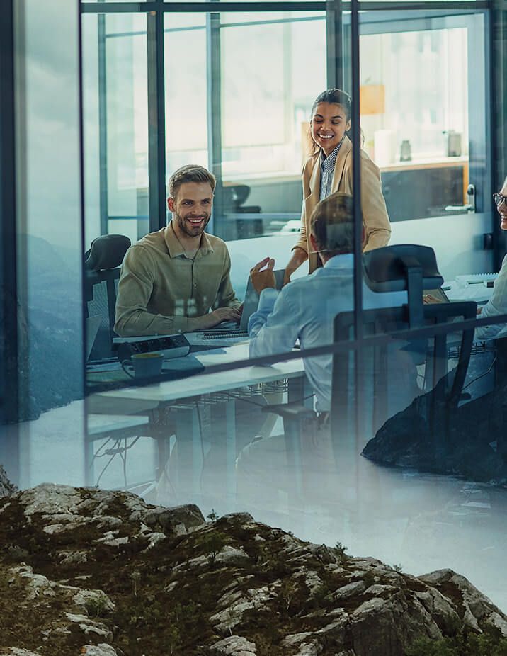 People in a meeting in a modern office; reflected mountain view in the glass.