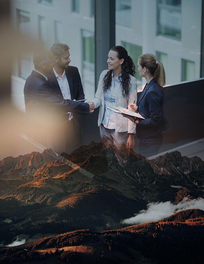 Businesspeople shake hands on a balcony overlooking mountains.