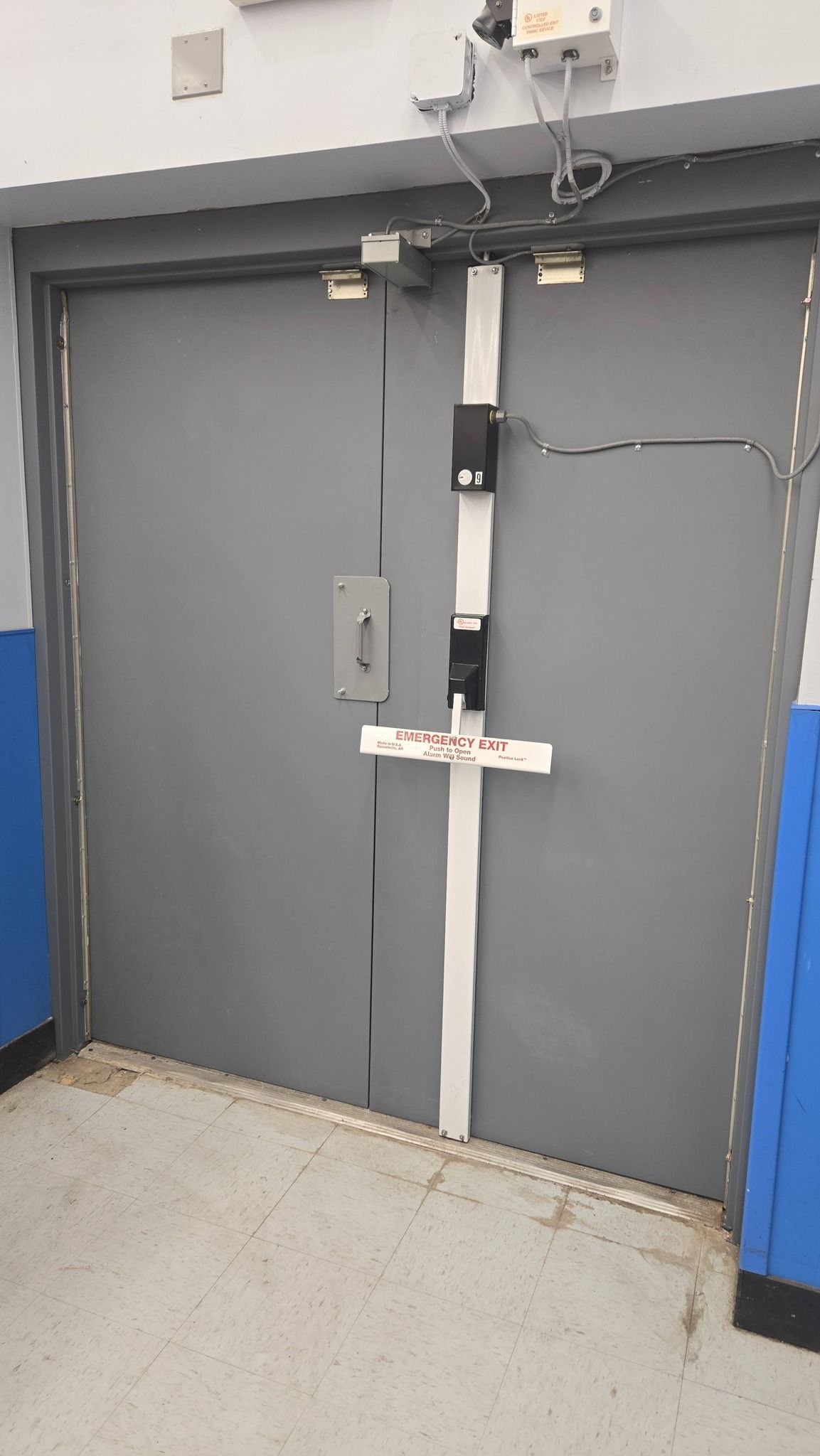 Gray double door with security hardware, white trim, and a concrete floor.