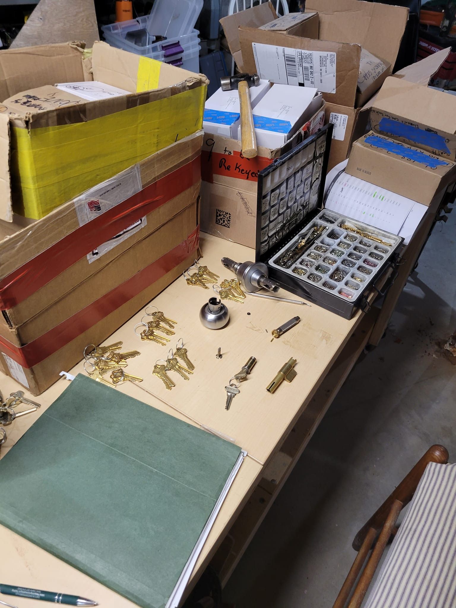 Table with open boxes, hardware, keys, and a green notebook.