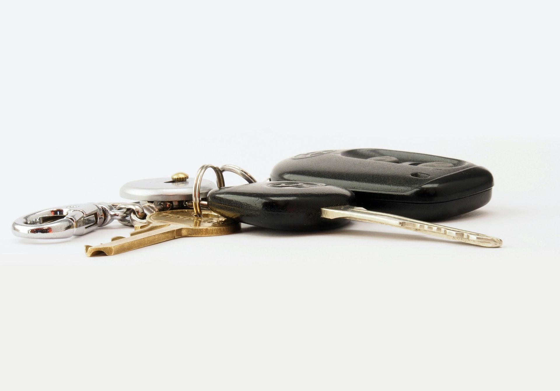 Keys on a white surface, including a car key and a remote.