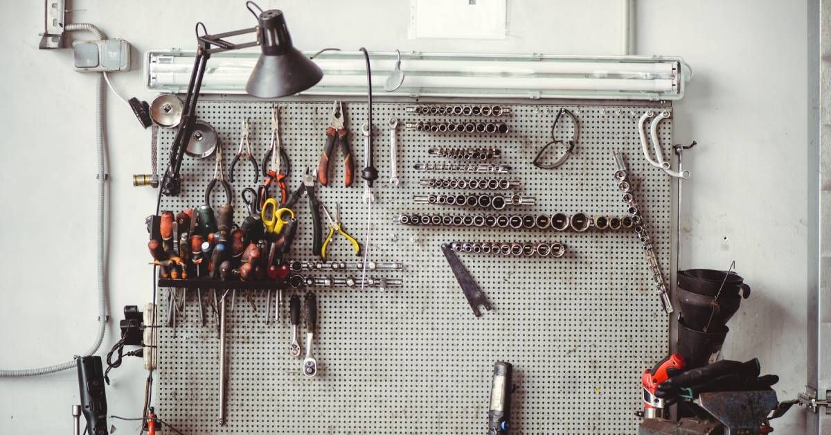 An automotive workbench filled with various tools. The workbench features built-in storage solutions like a peg board and drawers.