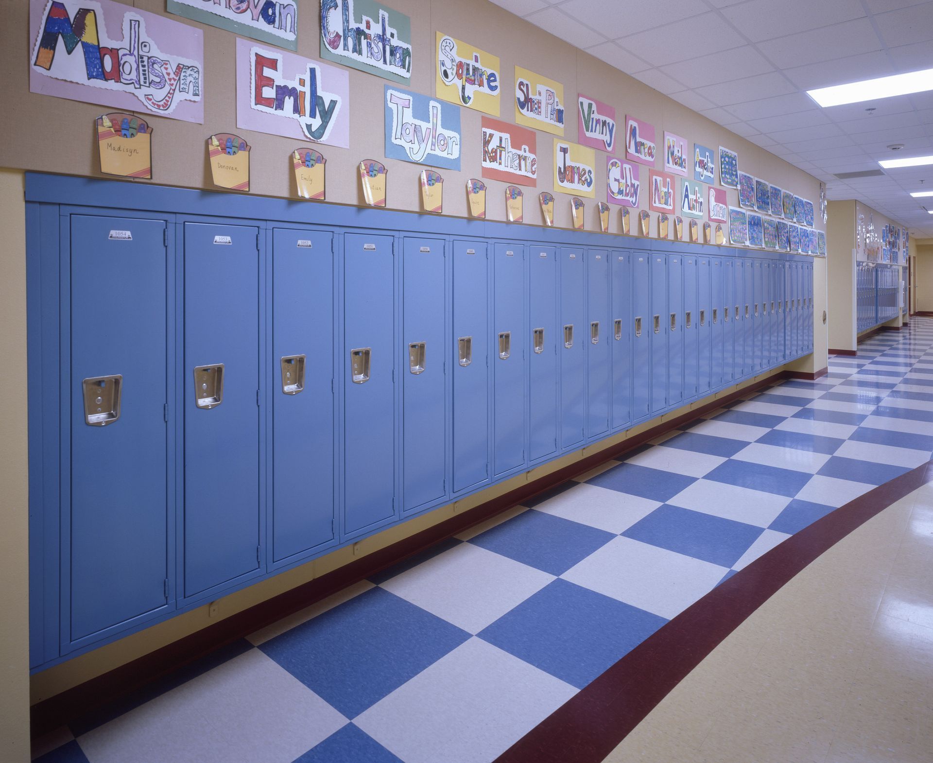 A row of blue lockers in a hallway with emily written on the wall