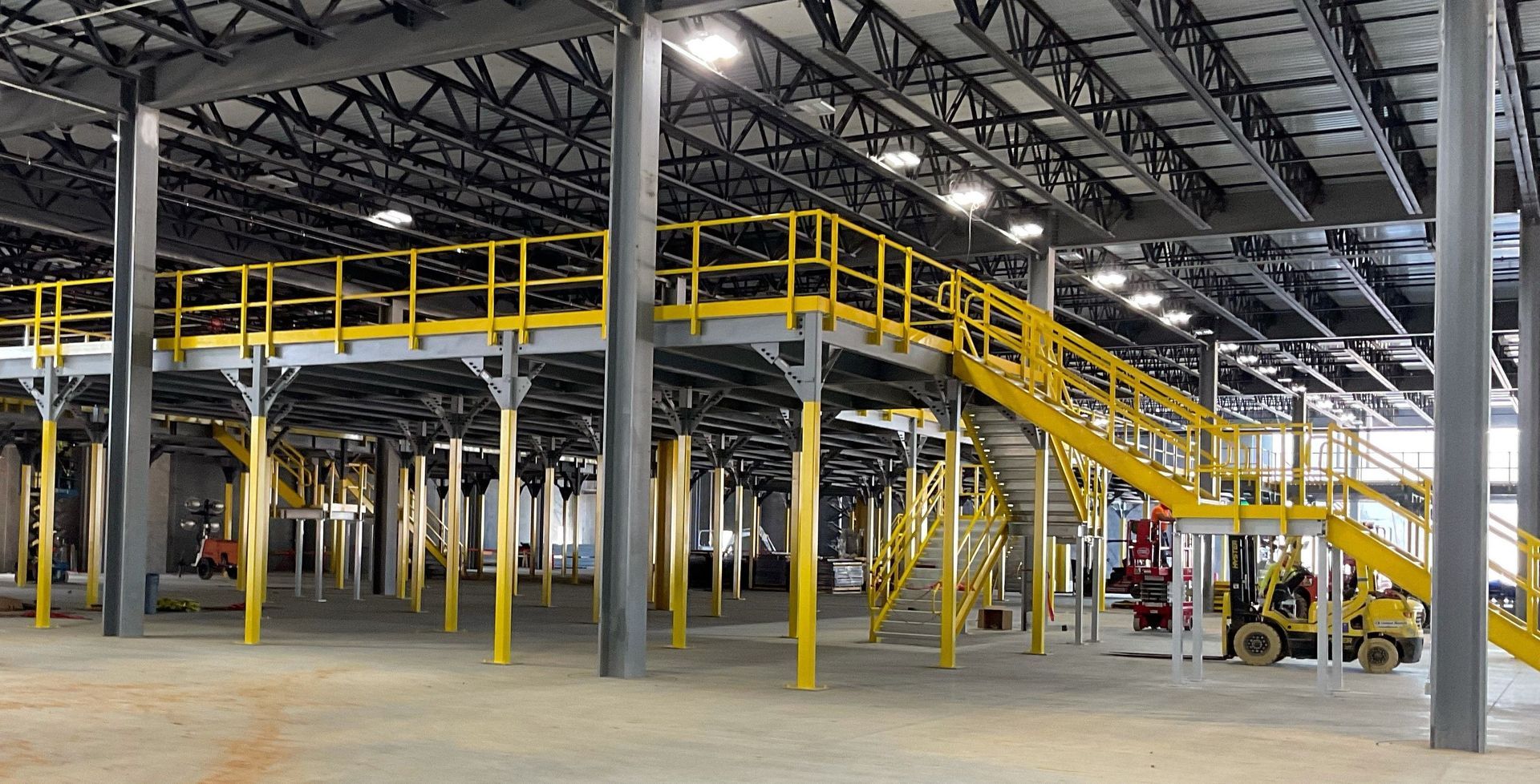 An empty warehouse with a yellow railing and stairs.