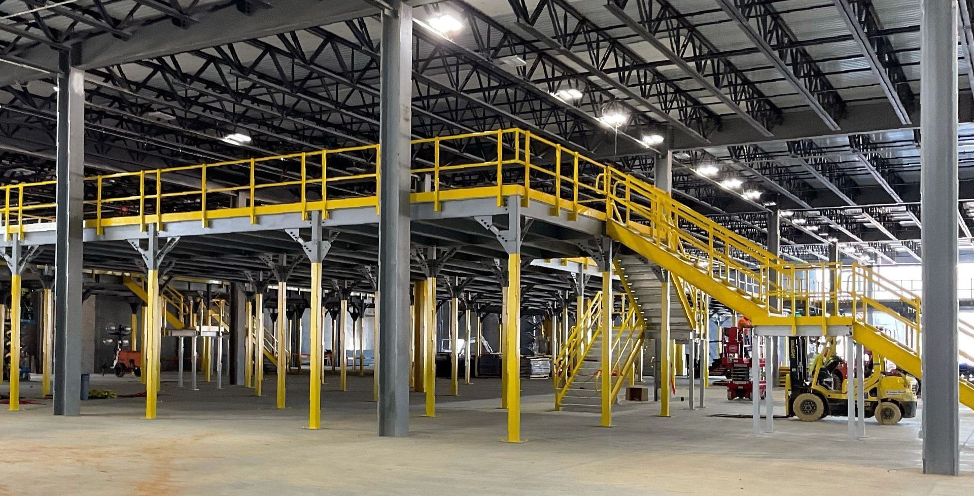 A large warehouse with a yellow staircase and a forklift.