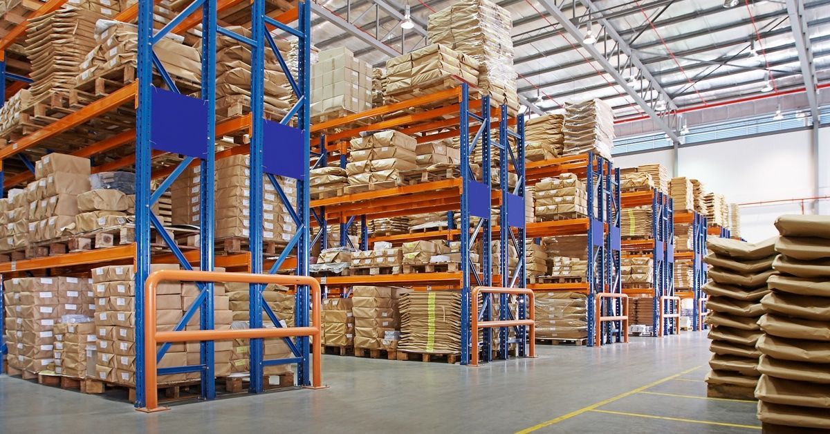 An interior view of a large, spacious warehouse that has rows of multilayered shelves stacked with c