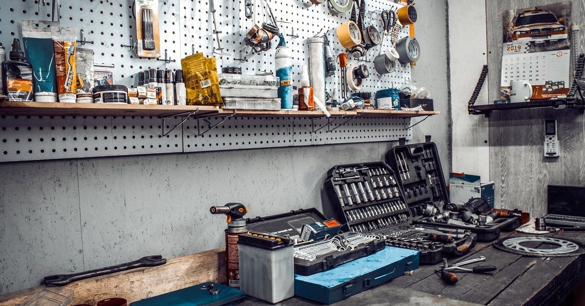 A close-up of a large workbench that is covered in various tools inside an automotive shop.
