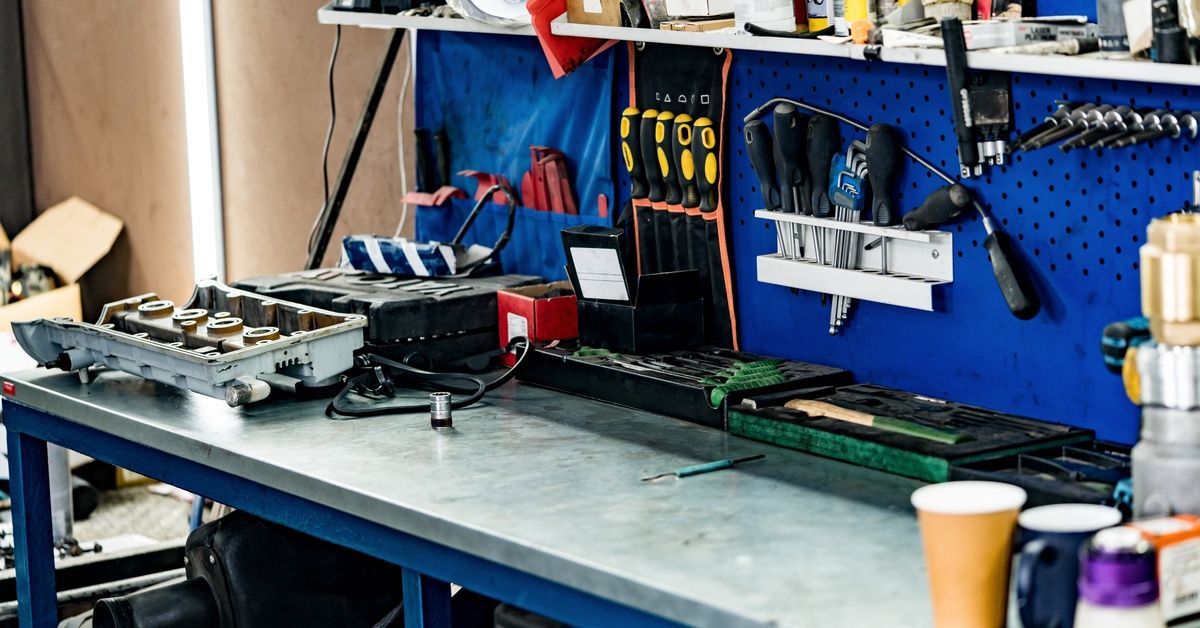 A large, heavy-duty work bench is covered in various tools and machinery in what appears to be a garage.