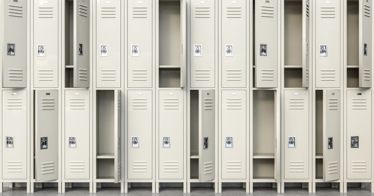 Two rows of metal school lockers stack on top of each other. Some of the doors are open while others are closed.