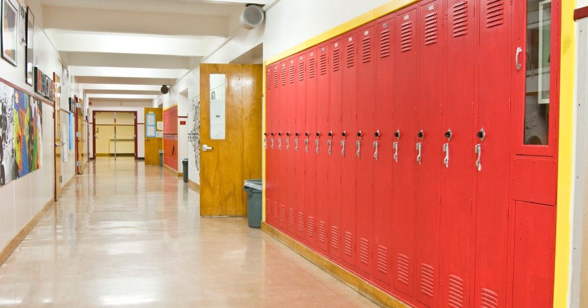 An empty school hallway with one wall holding tall red lockers.