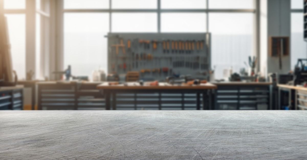 An empty table in an automotive workshop. Far behind it, neatly stacked, are blurry shelves and tools.