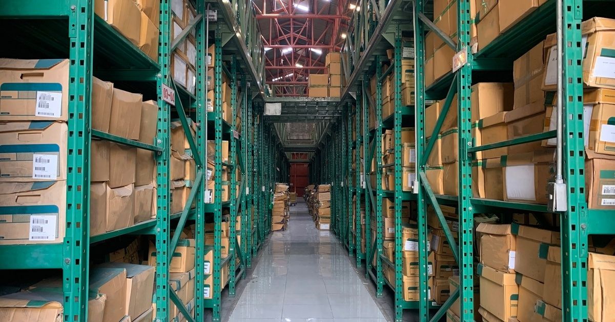 Large metal storage shelves that extend down a long pathway. The shelves are filled with document bi