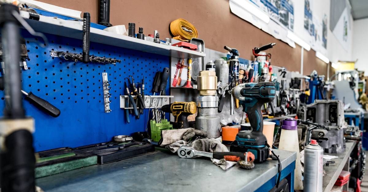 A compact automotive workbench in an auto repair workspace. The workbench features a tool peg board and storage drawers.