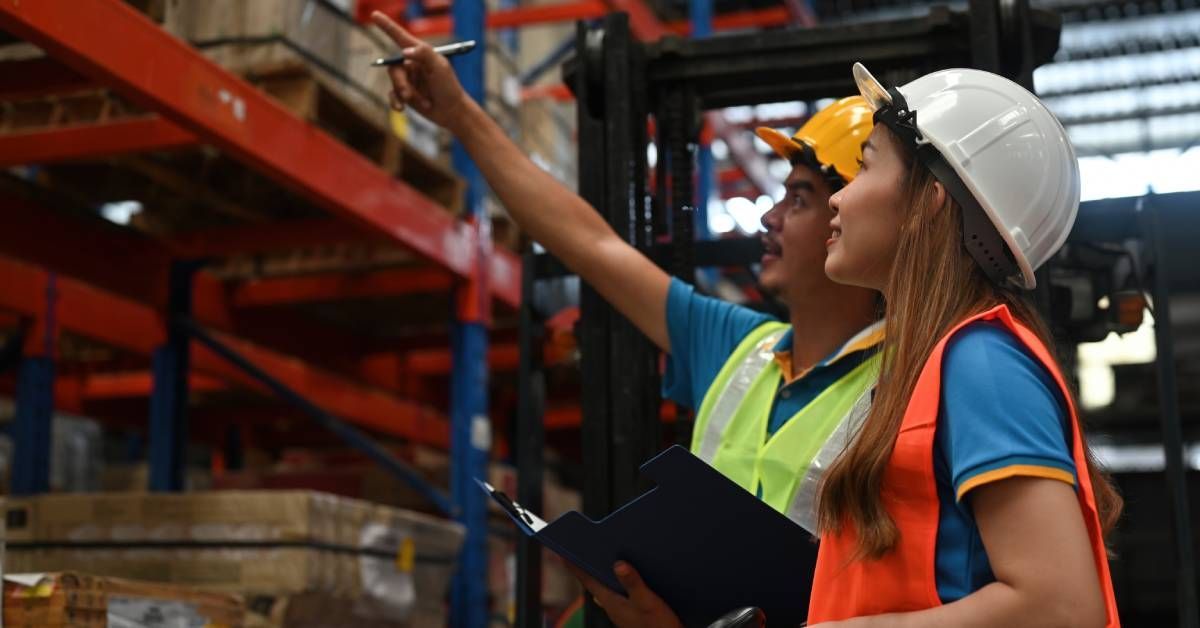 Two warehouse employees conducting a standard rack inspection of the warehouse's industrial racking system.