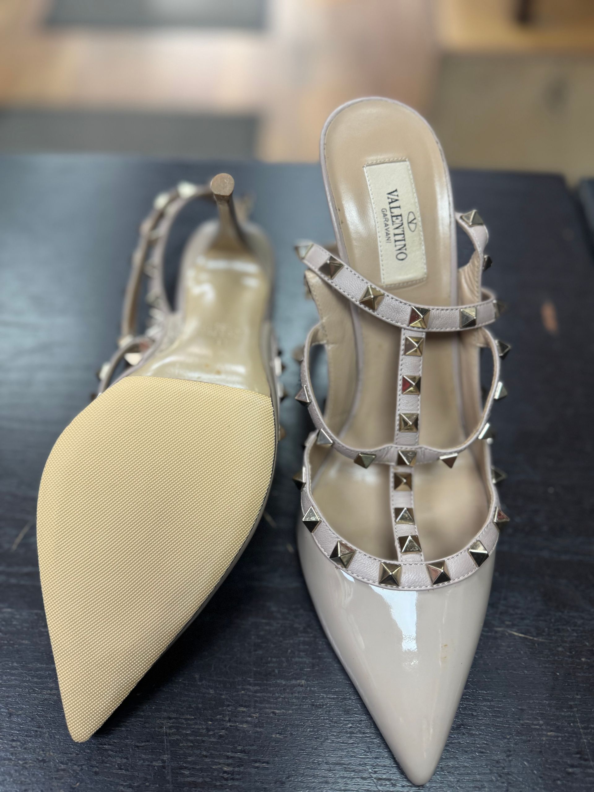 A pair of nude Valentino Rockstud stiletto heels, one showing the sole and one showing the studded T-strap design.