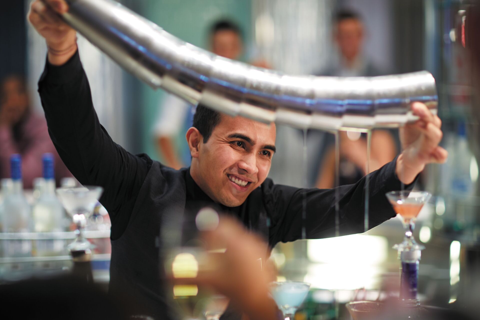 A bartender is shaking a drink in a martini glass.