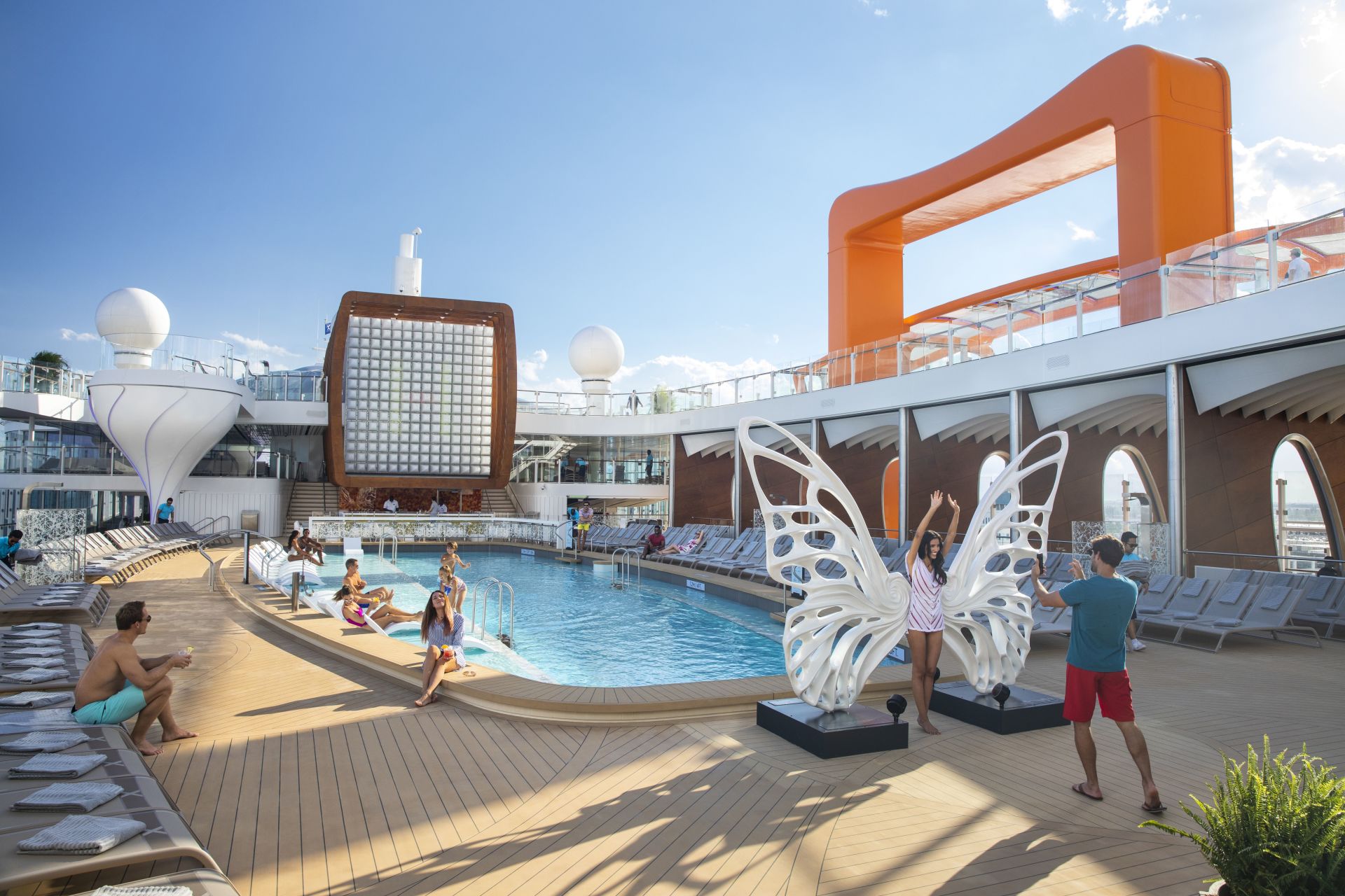 A group of people are standing around a swimming pool on a cruise ship.