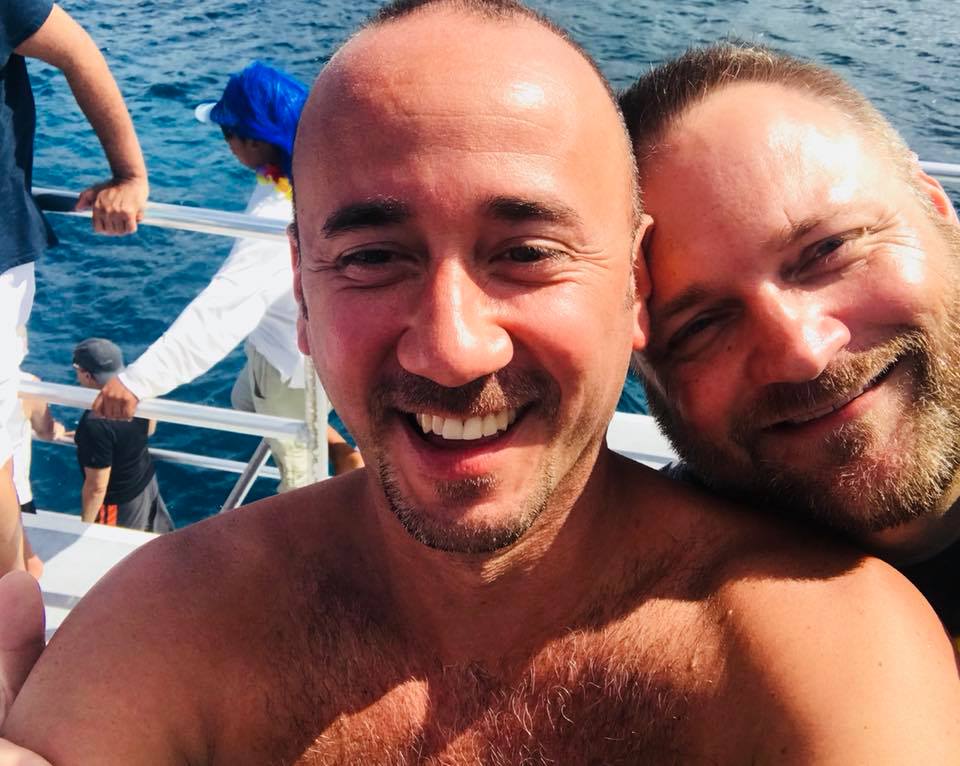 Two shirtless men are posing for a picture on a boat