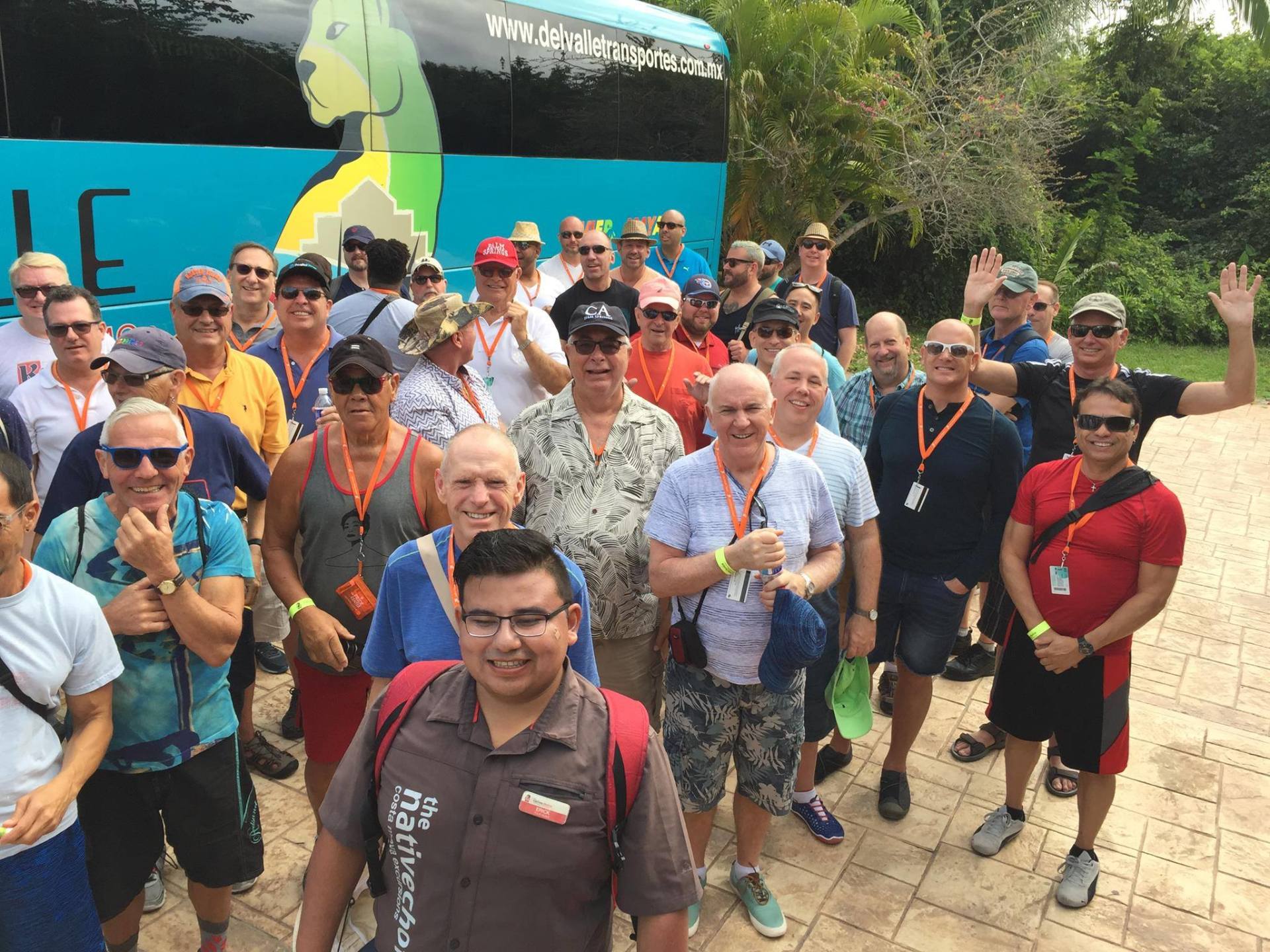 A group of men are posing for a picture in front of a bus that says le