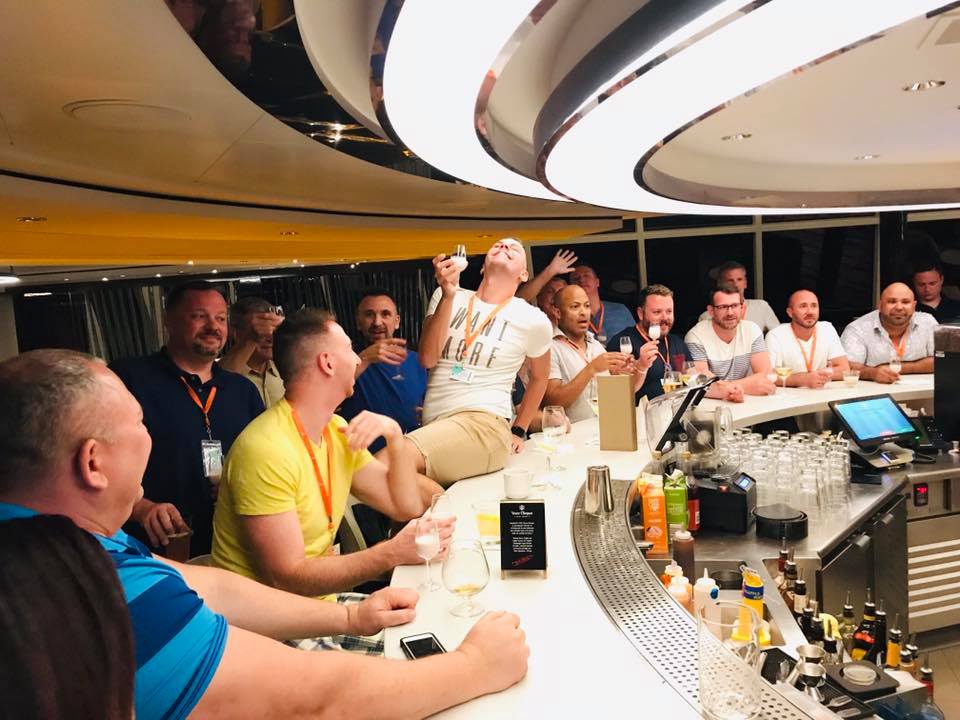 A group of men are sitting at a bar drinking and laughing.