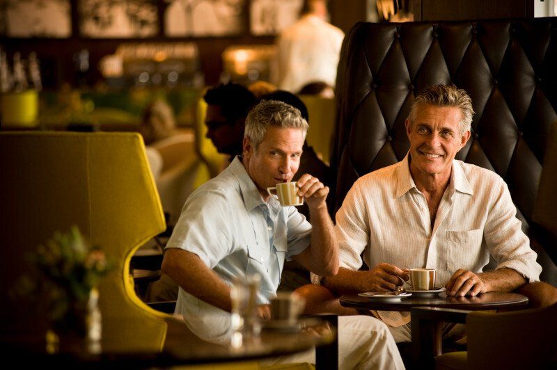Two men are sitting at a table in a restaurant drinking coffee.