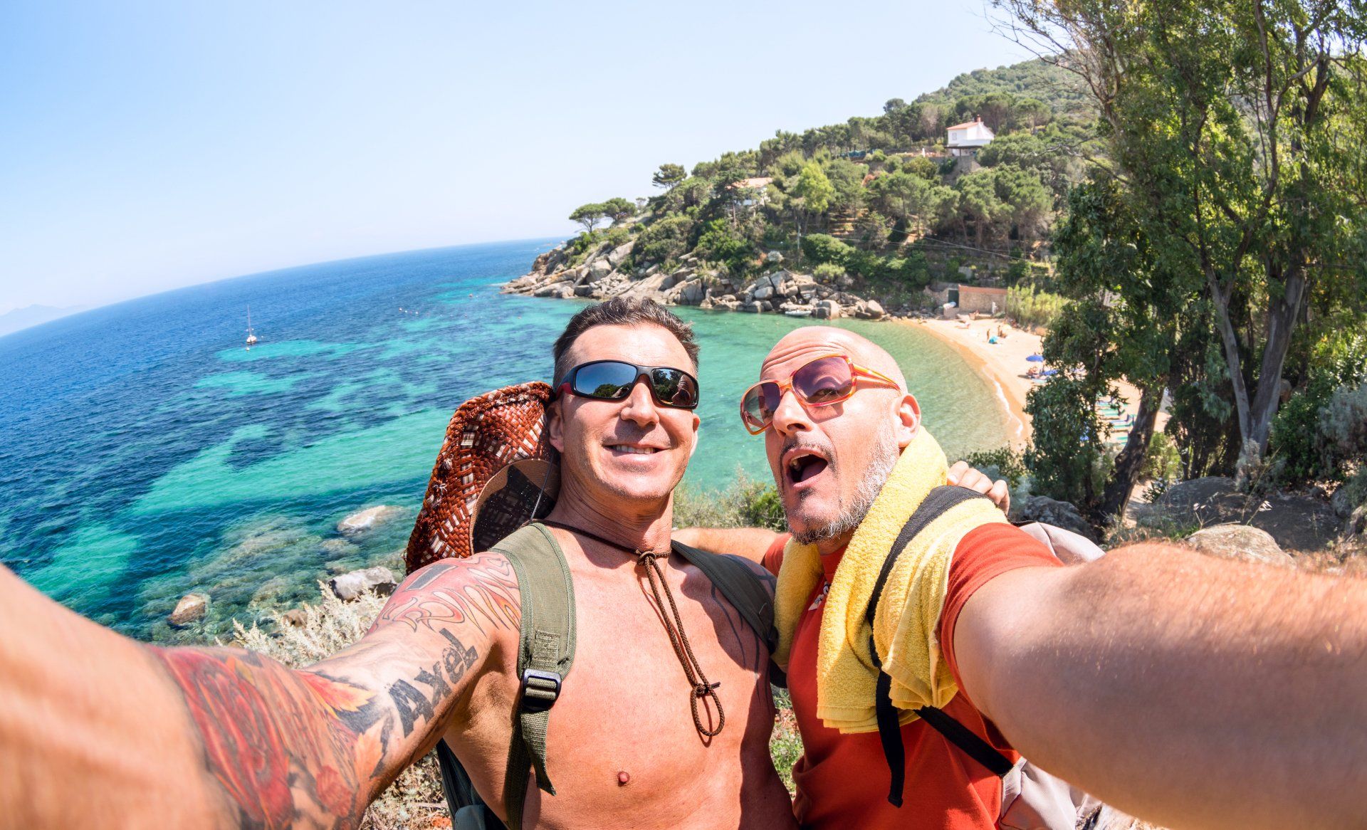 Two men are taking a selfie on a beach.