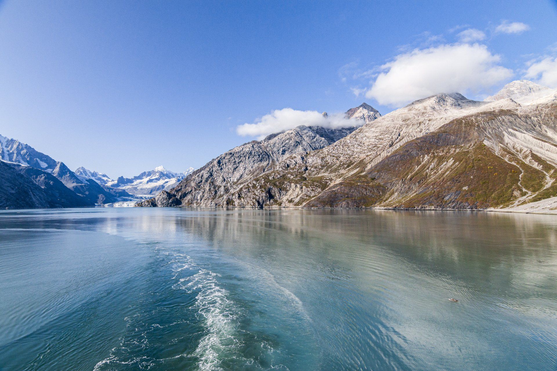 A boat is floating on a lake with mountains in the background.