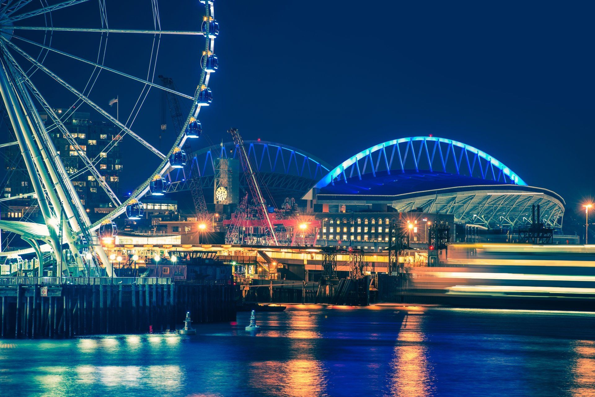 A ferris wheel is lit up at night in a city.