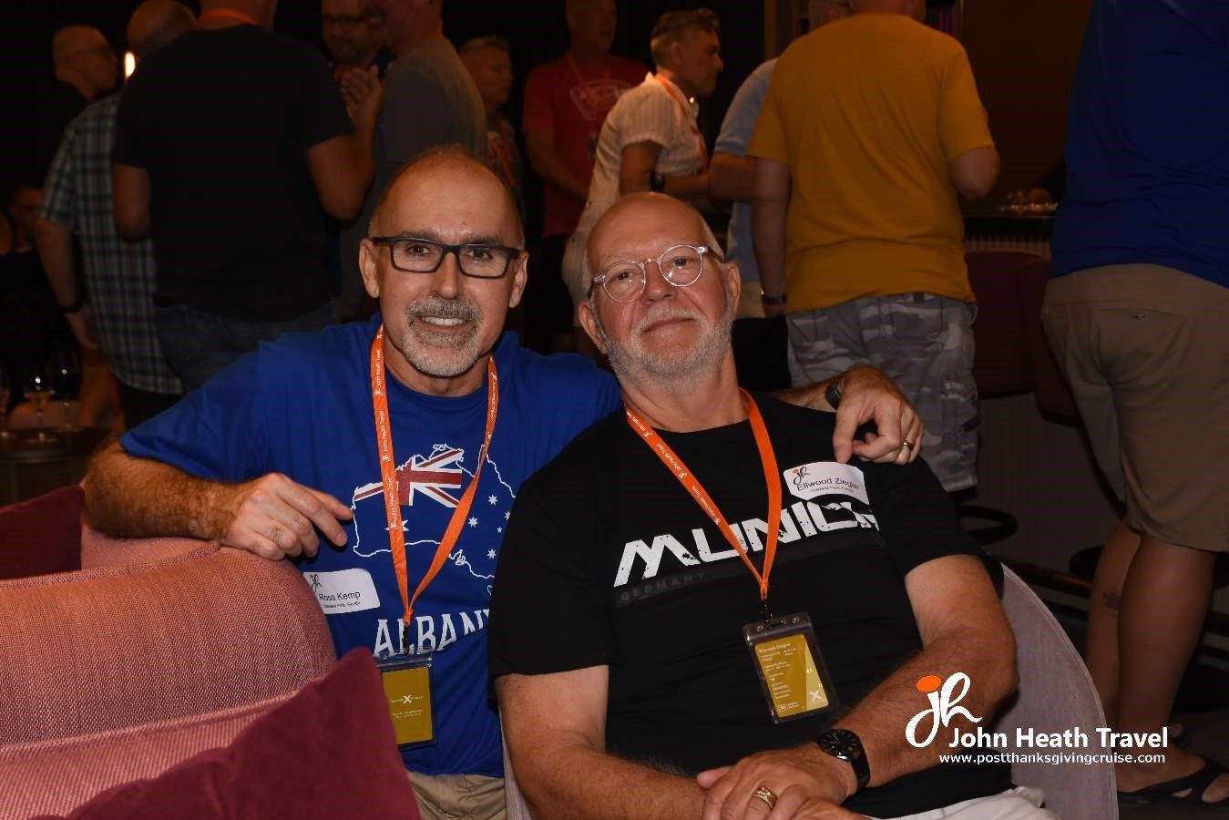 Two men are posing for a picture together in a crowded room.